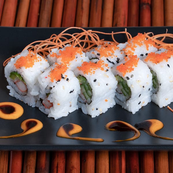 California sushi rolls with crab, avocado, and roe, garnished with carrot strings and sauces.